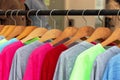 Multicolored shirts and sweatshirts hang on wooden hangers close up