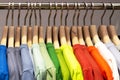 Multicolored shirts and sweatshirts hang on wooden hangers close-up