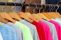 Multicolored shirts and sweatshirts hang on wooden hangers close-up side view