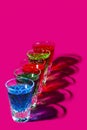 Multicolored shot glasses with Strong alcohol on pink background