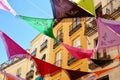 Multicolored Spanish shawls are strung between the balconies outside on the street. The decorated ambient creates a festive mood.