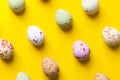 Multicolored speckled chocolate eggs arranged in isometric diagonal pattern on bright yellow background. Easter Royalty Free Stock Photo