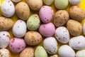 Multicolored speckled chocolate eggs arranged in pattern on bright yellow background. Easter card poster banner backdrop Royalty Free Stock Photo