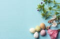 Multicolored speckled chocolate eggs bouquet of field flowers on light blue background with linen paper texture. Easter Royalty Free Stock Photo