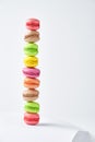 Multicolored stacked macarons on white background standing on white sheet of paper with copy space