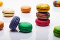 Multicolored stacked and separated macarons displayed on white background with reflection