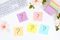 Multicolored stickers note with question mark on white desktop next to a mug of coffee and keyboard.