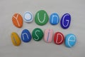 Young inside, message with colored stones over white sand