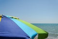 Multicolored sun umbrella against a blue sky on the sea beach Royalty Free Stock Photo