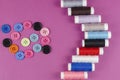 Multicolored thread spools and buttons on purple background Royalty Free Stock Photo