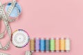 Multicolored threads of the coil, needle pins and centimeter on a pink background. Sewing supplies, patterns and Royalty Free Stock Photo