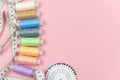 Multicolored threads of the coil, needle pins and centimeter on a pink background. Sewing supplies, patterns and Royalty Free Stock Photo