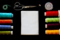 Multicolored threads, tape measure, scissors, pins and notepad for notes on a black background. View from above