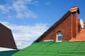 Multicolored tiled roofs of houses against the blue sky with clouds Background Attics Orange and green color.