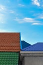 Multicolored tiled roofs of houses against the blue sky with clouds Background Attics Orange and green color Vertical