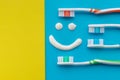 Multicolored toothbrushes on a blue and yellow background with a smile painted with toothpaste. The view from the top Royalty Free Stock Photo