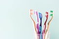 Multicolored toothbrushes in a glass cup, blue background