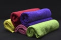 Multicolored towels on a black background. Terry towels. Colored rags in rolls. Rolled-up rags Royalty Free Stock Photo