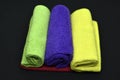 Multicolored towels on a black background. Terry towels. Colored rags in rolls. Rolled-up rags Royalty Free Stock Photo