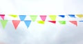Multicolored triangular flags hang on a string and flutter in the wind against a cloudy cloudy sky Royalty Free Stock Photo