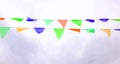 Multicolored triangular flags hang on a string and flutter in the wind against a cloudy cloudy sky Royalty Free Stock Photo