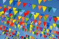 Multicolored triangular small flags to celebration party against blue sky as a background.Street holiday concept.
