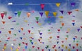 Multicolored triangular small flags to celebration party against blue sky with clouds as a background. Royalty Free Stock Photo