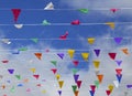 Multicolored triangular small flags to celebration party against blue sky with clouds as a background.