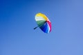 Multicolored umbrella flying suspended over bright blue sky background , with copy space