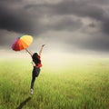 Multicolored umbrella woman jumping in green rice field and rainclouds Royalty Free Stock Photo