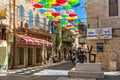 Multicolored umbrellas above narrow pedestrian street in Jerusalem.