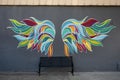 Multicolored wings above a black iron bench for self photographs in historic downtown Sherman, Texas.