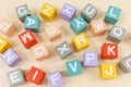 Multicolored wooden cubes with the alphabet on the beige table. Trendy puzzle toys. Geometric shapes. Back to school. Education