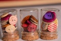 Multicolored wooden round sewing buttons in small jars macro shot. Royalty Free Stock Photo