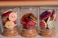 Multicolored wooden round sewing buttons in small jars macro shot. Royalty Free Stock Photo