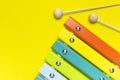 Multicolored wooden xylophone and shock sticks on bright yellow background flat lay top view copy space. Wooden children`s musica Royalty Free Stock Photo