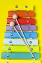Multicolored wooden xylophone and shock sticks on bright yellow background flat lay top view copy space. Wooden children`s musica Royalty Free Stock Photo