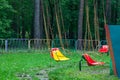 Multicolored yellow and red plastic seats hanging on the chains carousel in the park for entertainment and fun for children and Royalty Free Stock Photo