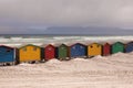 Multicoloured beach huts on beach with ocean in the background