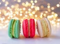 multicoloured macarons with cream on white surface, golden bokeh effect behind Royalty Free Stock Photo