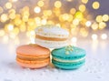 multicoloured macarons with cream and almonds on white surface, golden bokeh effect behind Royalty Free Stock Photo