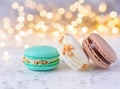 multicoloured macarons with cream and almonds on white surface, golden bokeh effect behind Royalty Free Stock Photo