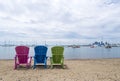 Multicoloured Muskoka Cottage chairs on the sand the beach looking out to the harbor and downtown Etobicoke in the background Royalty Free Stock Photo