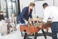 multicultural businessmen playing table football while businesswomen having conversation during break Royalty Free Stock Photo