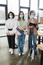 Multicultural businesswomen in protective masks holding