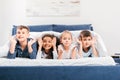 multicultural children looking at camera while lying together in bed Royalty Free Stock Photo
