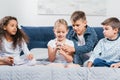 multicultural children with smartphone resting together on bed Royalty Free Stock Photo