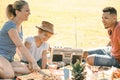 Mixed race family on picnic in park on a sunny day. smiling blond wife cutting a sweet, black husband and cute mixed race child Royalty Free Stock Photo