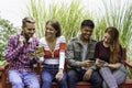 Multicultural friends having fun together looking at their smartphones  at dehor garden on college campus - People addicted by Royalty Free Stock Photo