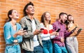 Multicultural friends laughing using smartphone at wall on university college campus - Young people addicted by mobile phone Royalty Free Stock Photo